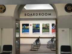 Entrance to a boardroom with chairs lined up and posters on the wall. The word BOARDROOM is visible above the entrance.
