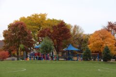 Playground equipment and colorful autumn trees at Longfellow Park.